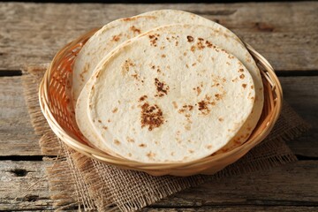 Tasty homemade tortillas in wicker basket on wooden table