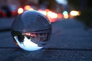 Beautiful city street, overturned reflection. Crystal ball on asphalt road outdoors, closeup. Space...