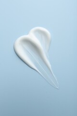 Sample of face cream on light blue background, top view