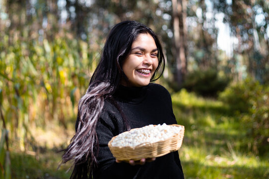 La cosecha del esfuerzo,una campesina bonita orgullosa muestra el fruto de su trabajo en la tierra, sosteniendo en su mano una canasta rebosante de ma&iacute;z,alegre mujer,trabajo,estilo de vida