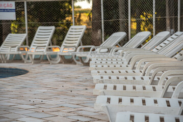 White lounge chairs in a swimming pool environment.