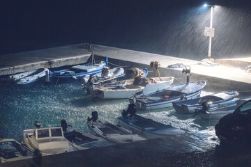 Fishing boats moored during heavy rain, storm at night, sea