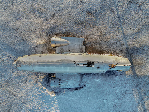 Aerial view of a crashed airplane in the snowy landscape of Iceland