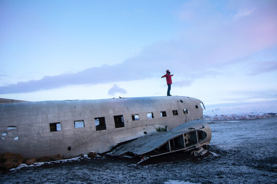 Person standing atop a crashed plane in snowy Iceland