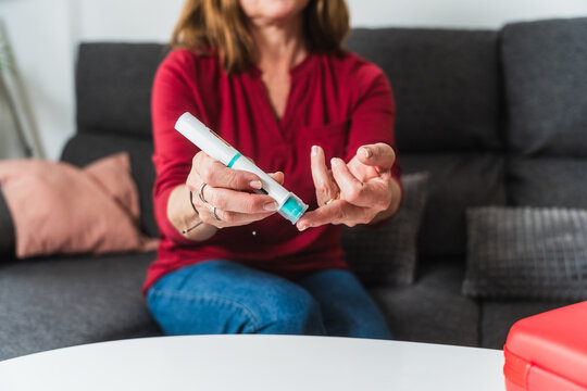 Woman checking blood sugar level at home - Powered by Adobe