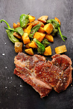 Grilled steak and roasted vegetables on slate background