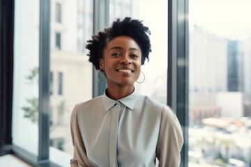confident young black businesswoman standing at a window in an office alone