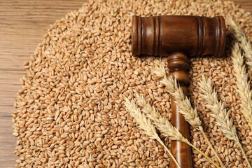 Judge's gavel, wheat ears and grains on wooden table, closeup. Agricultural deal