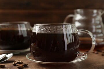 Hot coffee in glass cups and beans on wooden table, closeup