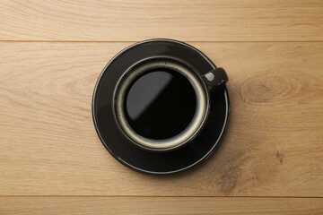 Hot coffee in cup on wooden table, top view