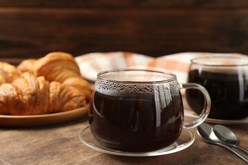 Hot coffee in glass cup on wooden table, closeup