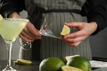 Woman making delicious Margarita cocktail at grey table, closeup