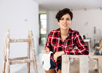 Portrait of young attractive woman engineer standing with construction gloves on construction site...