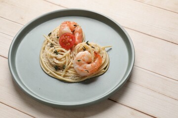 Heart made of tasty spaghetti, tomato, shrimps and cheese on light wooden table