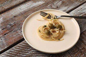 Heart made of tasty spaghetti, fork, olives and cheese on wooden table