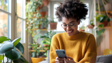 A cheerful woman with stylish glasses and a puff of curly hair is engrossed in her smartphone while sitting in a cozy indoor setting with natural light - Generative AI