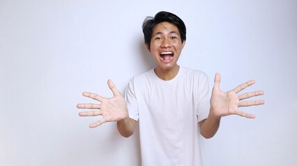 Young Asian man in white shirt with funny expression, excited, laughing with open hand gesture