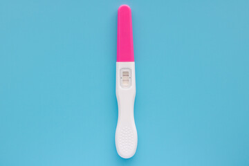 A white pregnancy test is isolated over a blue background. Women's health, fertility, planning maternity and pregnancy concept. Stack of test kits with positive results. Copy space for advertising.