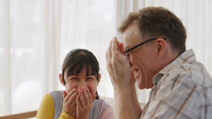 Grandfather and granddaughter together talking about entertainment media on TV. Old senior use...