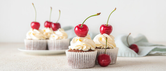 Tasty cherry cupcakes on light background