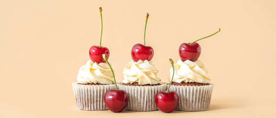 Tasty cherry cupcakes on beige background