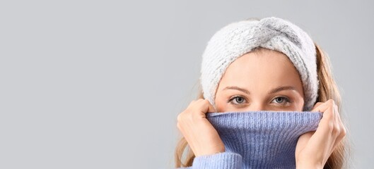 Frozen beautiful young woman in warm clothes on grey background with space for text