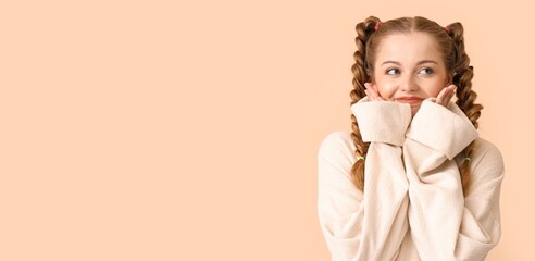 Beautiful happy young woman in warm sweater on beige background with space for text