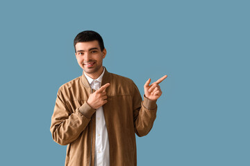 Young man pointing at something on blue background