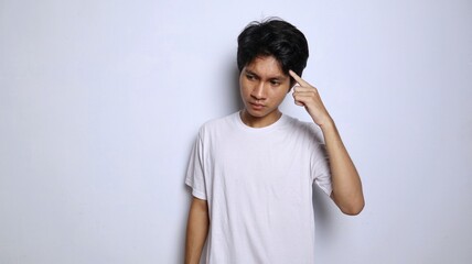 young asian man in white shirt with serious expression is thinking about something