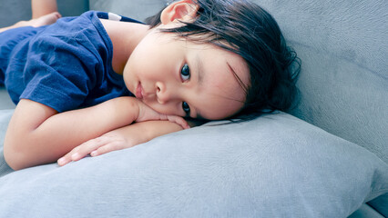 lazy and sleepy little Asian boy on the couch
