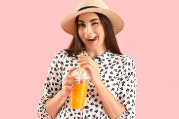 Young woman with glass of juice on pink background