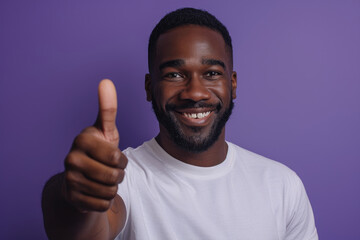 Photo of a happy black man wearing a casual t-shirt showing thumbs up on a purple studio background