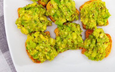 On table in cafe there is plate with traditional Mexican snack - guacamole sandwich. Salty and...