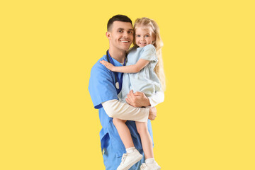 Male pediatrician with little girl on yellow background
