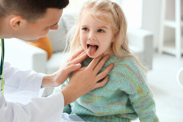 Male pediatrician examining little girl in clinic
