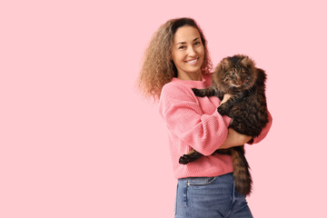 Happy mature woman with cute cat on pink background