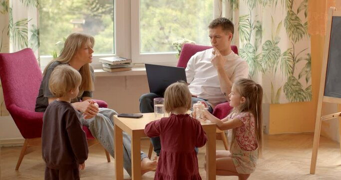 Work and family life. Father sits with laptop, children play around him. Despite being occupied, he remains present and engaged with family. Balancing professional responsibilities with family time - Powered by Adobe