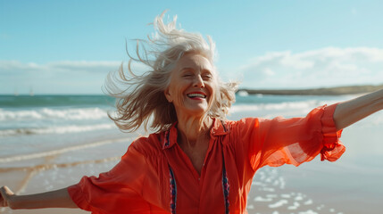 A mature woman is dancing happily on the sandy beach with her arms outstretched under the bright sun