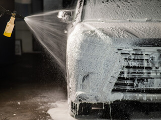 Man applying foam to black car in car wash. 