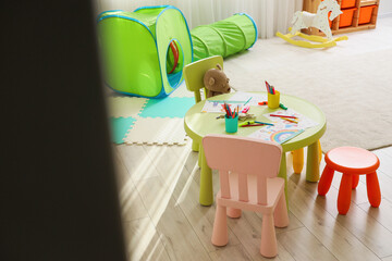 Interior of playroom with drawings on table in kindergarten