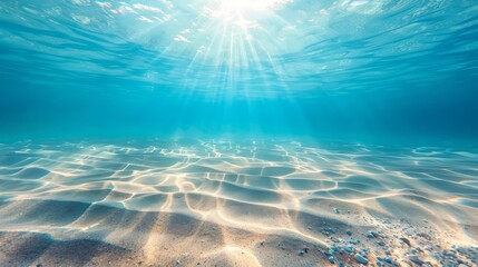 Seabed sand with blue tropical ocean above, empty underwater background with the summer sun shining brightly, creating ripples in the calm sea water