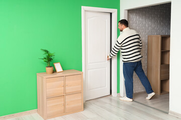 Young man opening white door in room