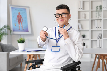 Young male doctor in wheelchair with stethoscope at hospital