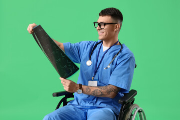 Young male doctor in wheelchair with x-ray image on green background