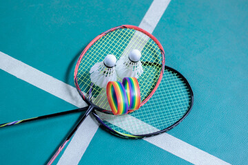 Rainbow wristbands, used cream white badminton shuttlecock and racket placed on floor in indoor...