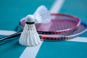 Badminton sport equipments, rackets and shuttlecocks on dark floor of indoor badminton court, soft...