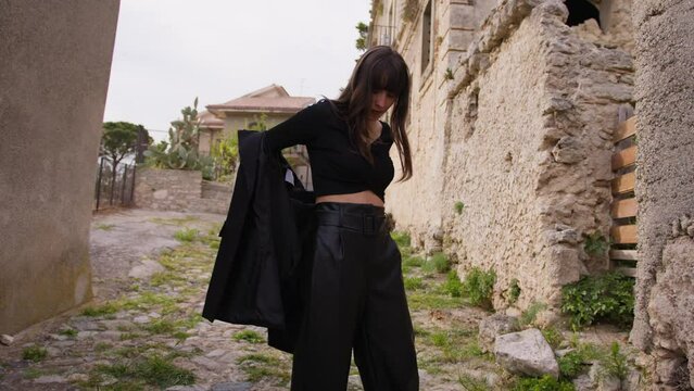 Girl Takes Off Her Black Jacket In A Street Of A Village