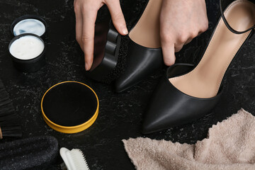 Hands cleaning shoes with brush on black grunge background
