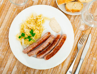 Delicious fried sausage served with pickled cabbage on plate