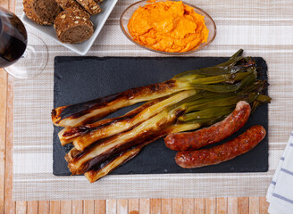 Traditional Catalan calcotada meal. Calcots roasted over open fire on slate serving board with...
